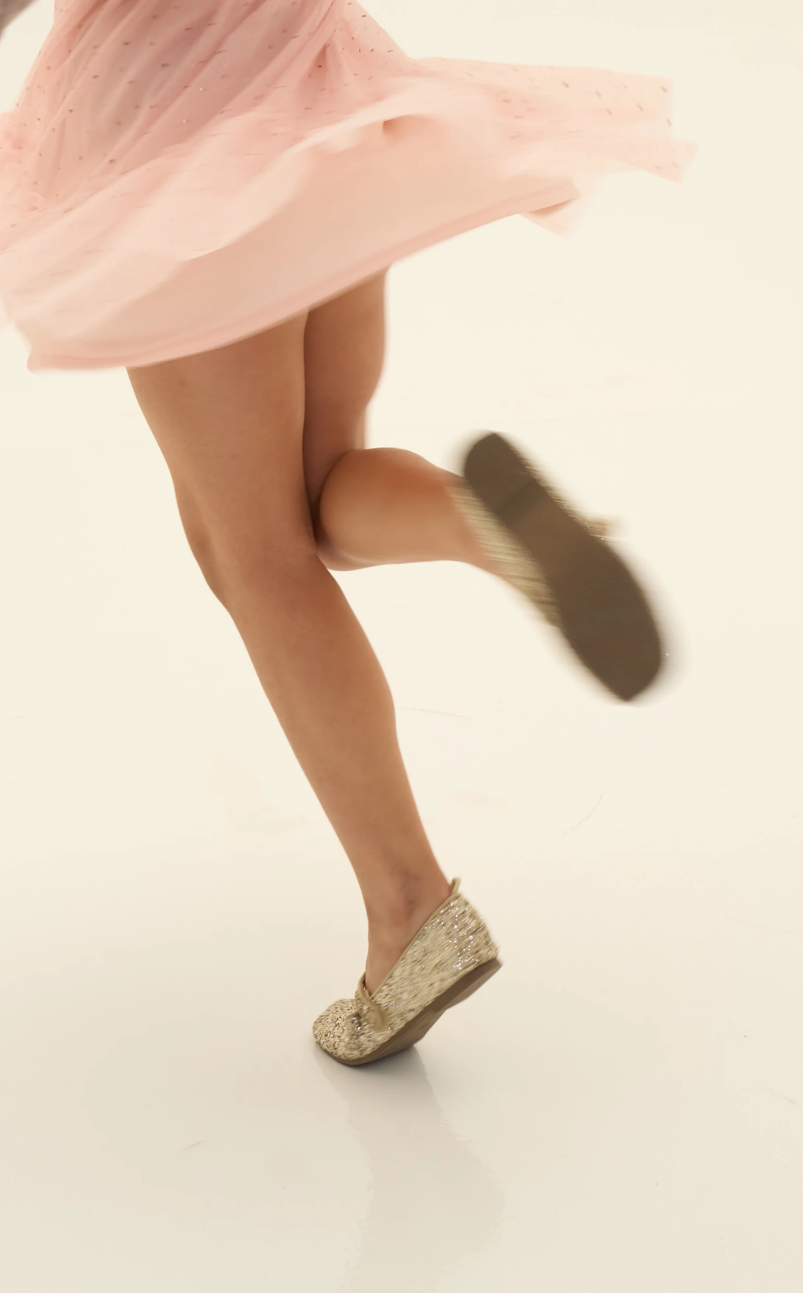 A girl mid-skip in a tulle skirt and glitter shoes